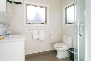 Une salle de bain moderne équipée de toilettes, d’un lavabo et de deux fenêtres.