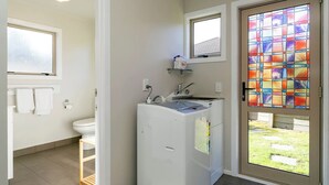 A compact bathroom with a toilet, a sink, and a window. - Mercy of Lake Taupo- family time + lake time (Taupo)