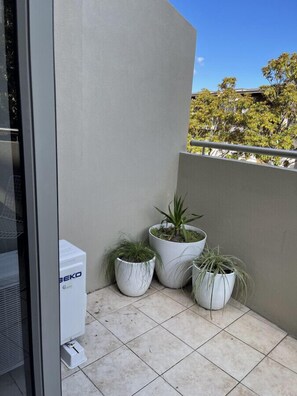 Enjoy the serene view from this balcony, featuring a selection of potted plants and a comfortable outdoor space.