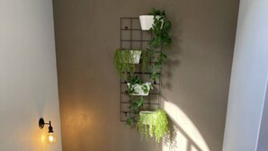 A staircase with a wooden handrail, a wall-mounted plant shelf, and a wall sconce. - Tui Unit - So close to the lake +Pool (Taupō)