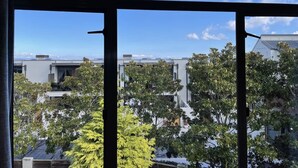 A view from a window with a clear sky, modern buildings, and lush green trees. - Tui Unit - So close to the lake +Pool (Taupō)