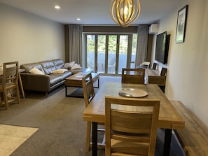 Relax in this inviting living room with a large dining table, comfortable sofa, and flat-screen TV.