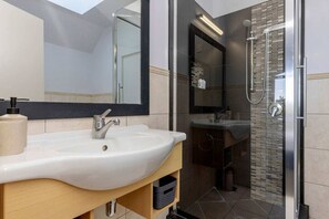 Ein modernes Badezimmer mit einem großen Waschbecken, einem Spiegel und einer Dusche.