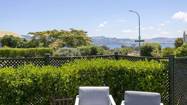 A view from a balcony with a wooden lattice fence, two grey lounge chairs, and a street sign indicating 'Whalley' road.
