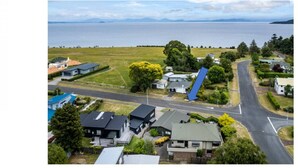An aerial view of a residential area with houses, a road, and a body of water in the background.