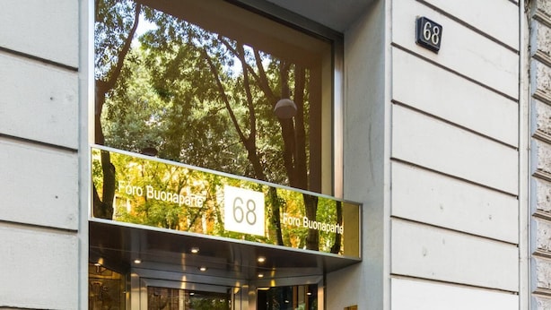 A building entrance with a glass door, a number '68' sign, and a small plaque on the wall.