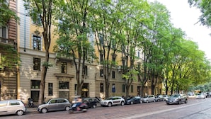 A street lined with parked cars and trees, with buildings on either side.
