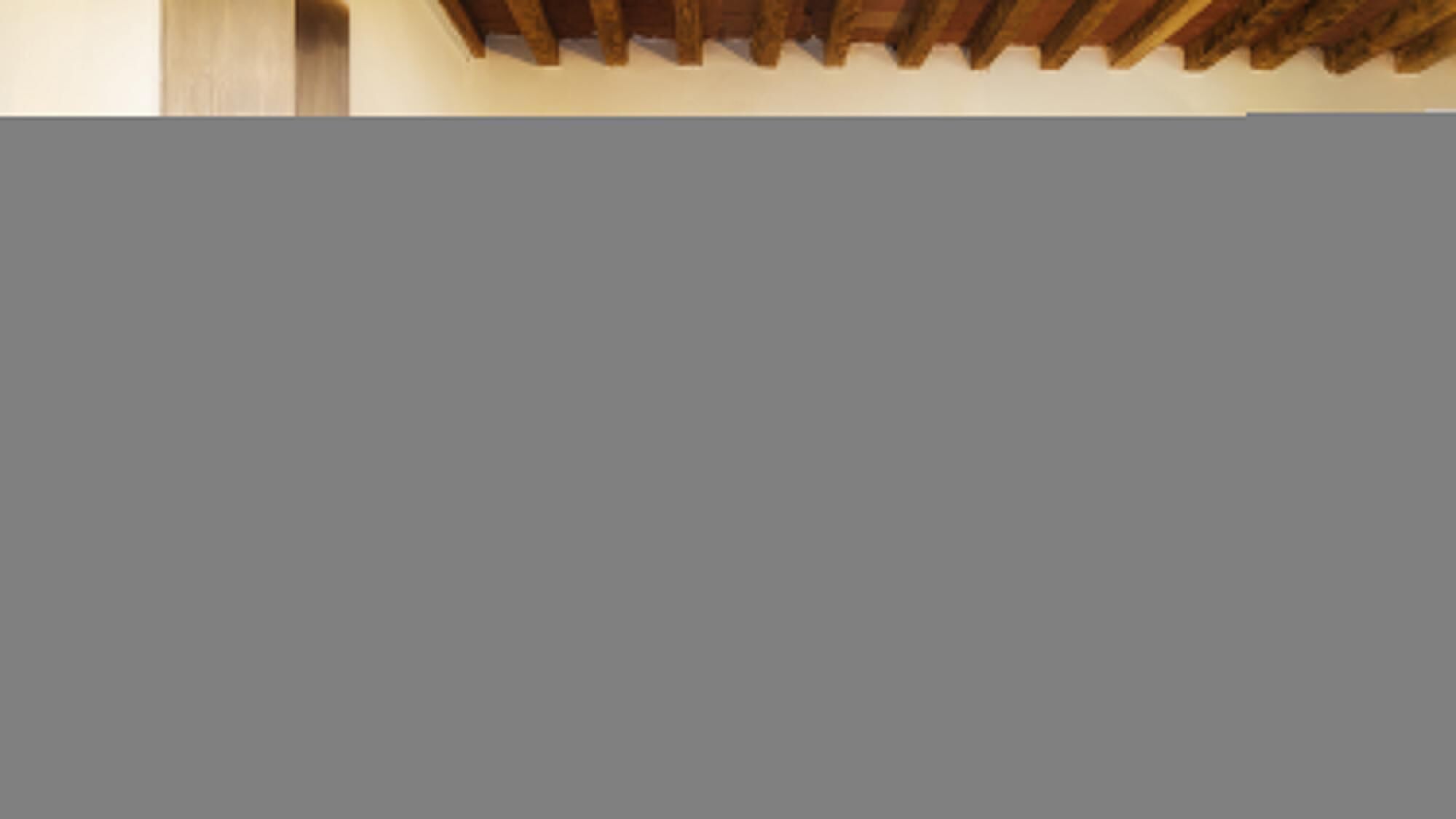 Un soffitto con travi in legno e una parete semplice.