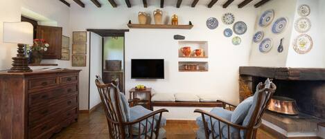 Uma sala de estar aconchegante com móveis de madeira, lareira e pratos decorativos na parede.
