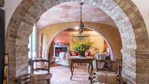 A cozy room with a brick archway, a wooden table with a vase of yellow flowers, and two upholstered chairs. - Molino L Oppino 6 in Torrita di Siena (Torrita di Siena)