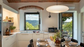 A modern kitchen with a large window, a built-in oven, and a dining area set for four.