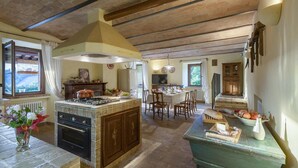 A spacious kitchen with a central island, wooden cabinets, and a dining area with a table and chairs. - Villa Il Baiocco 8 in Ospedaletto (Urbino)