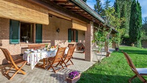 A patio with a table set for breakfast, surrounded by brick walls and green shutters. - Villa Il Baiocco 8 in Ospedaletto (Urbino)