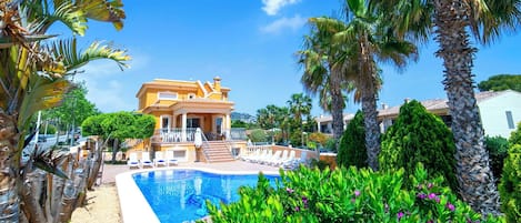 A resort with a swimming pool, palm trees, and a large building with a balcony.