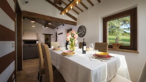 Comedor con una mesa dispuesta para cuatro, un jarrón de flores y vista a plantas al exterior.