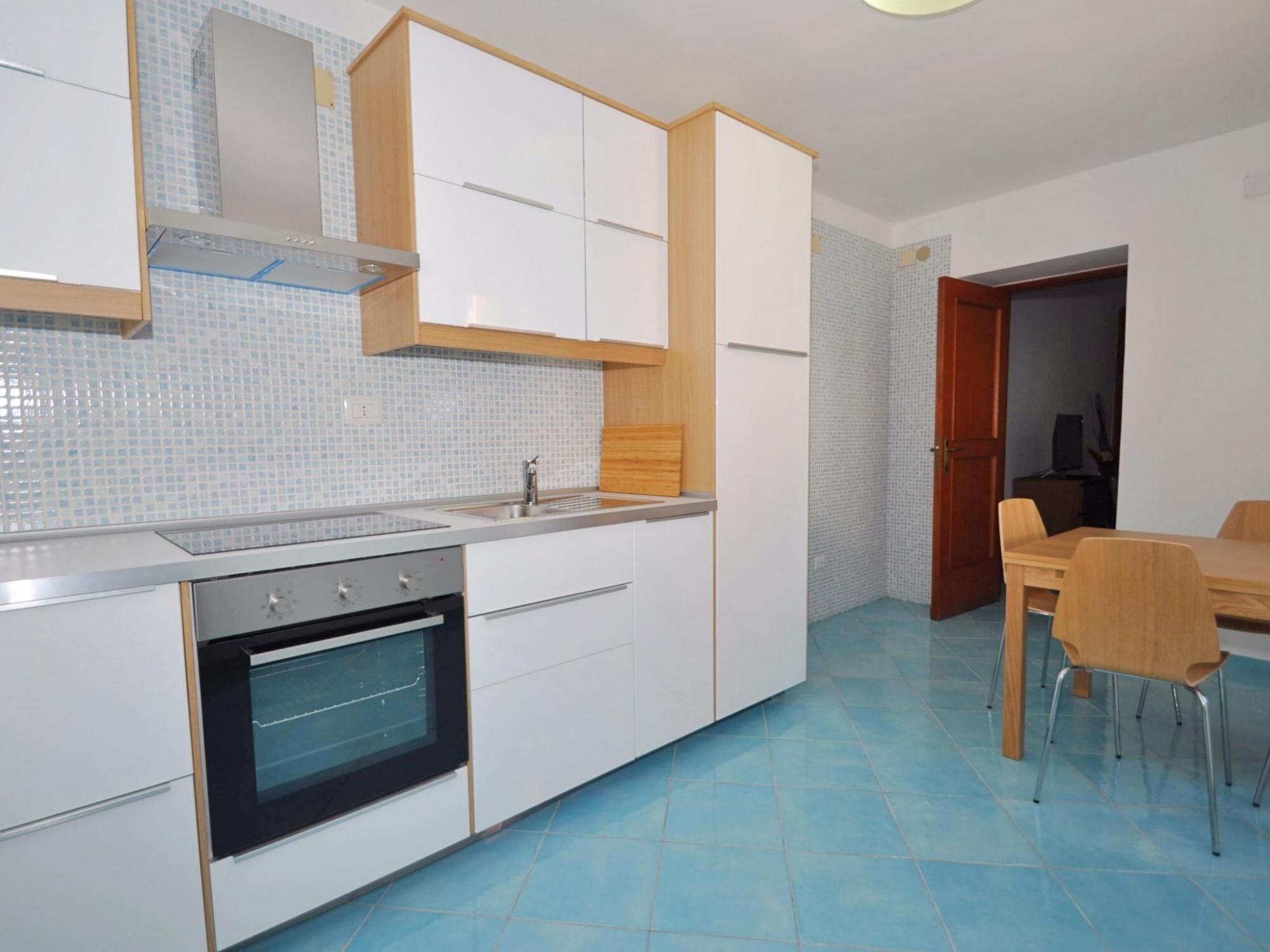 A modern kitchen with white cabinets, a built-in oven, and a tiled backsplash.