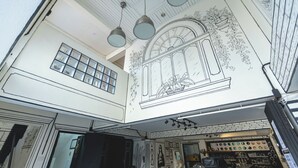 A high-ceiling interior with hanging lights, a large window, and a wall with a detailed drawing. - RoomQuest Chiang Mai Tha Phae (Chiang Mai)
