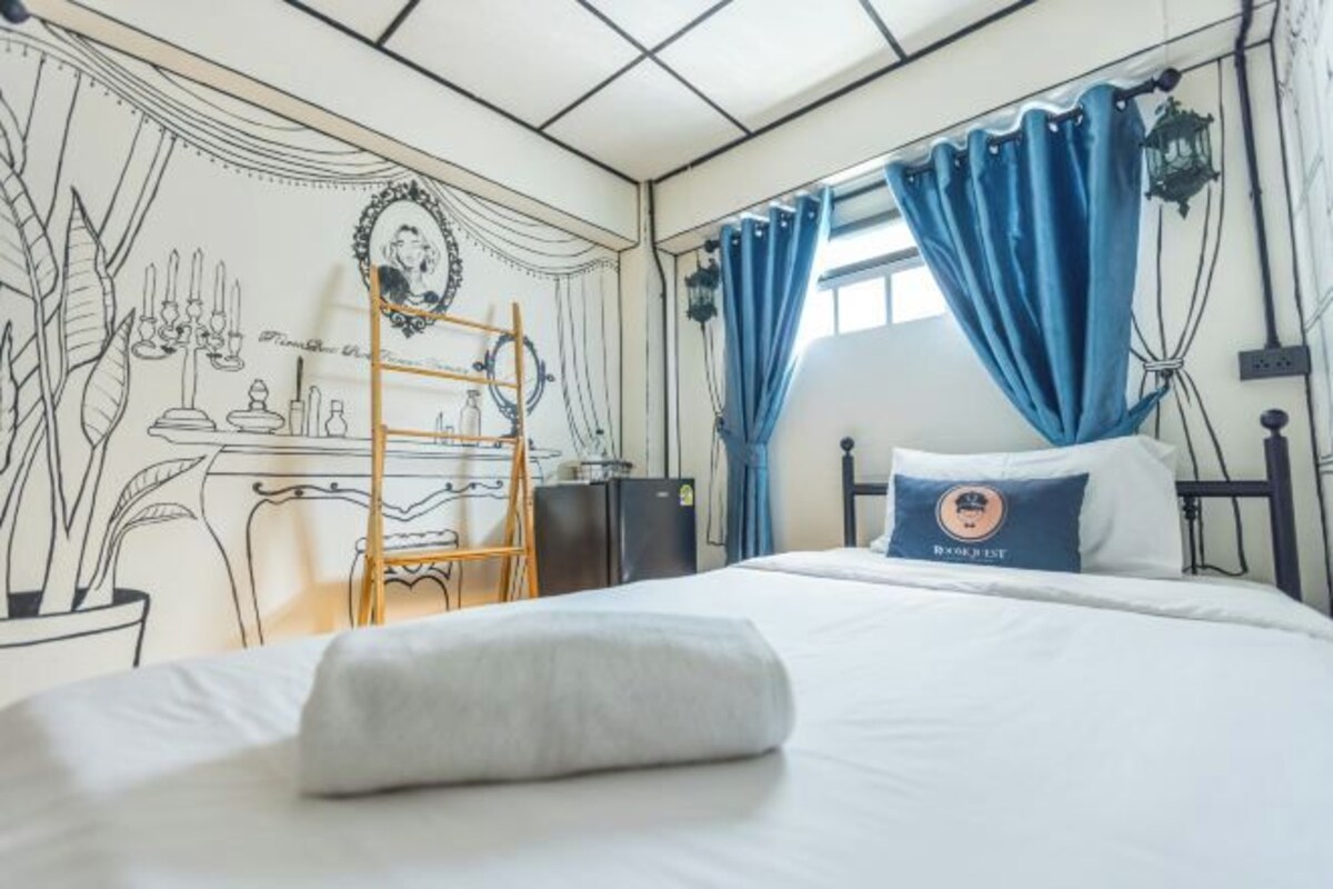 A bedroom with a bed, a desk, a ladder, and a window with curtains.
