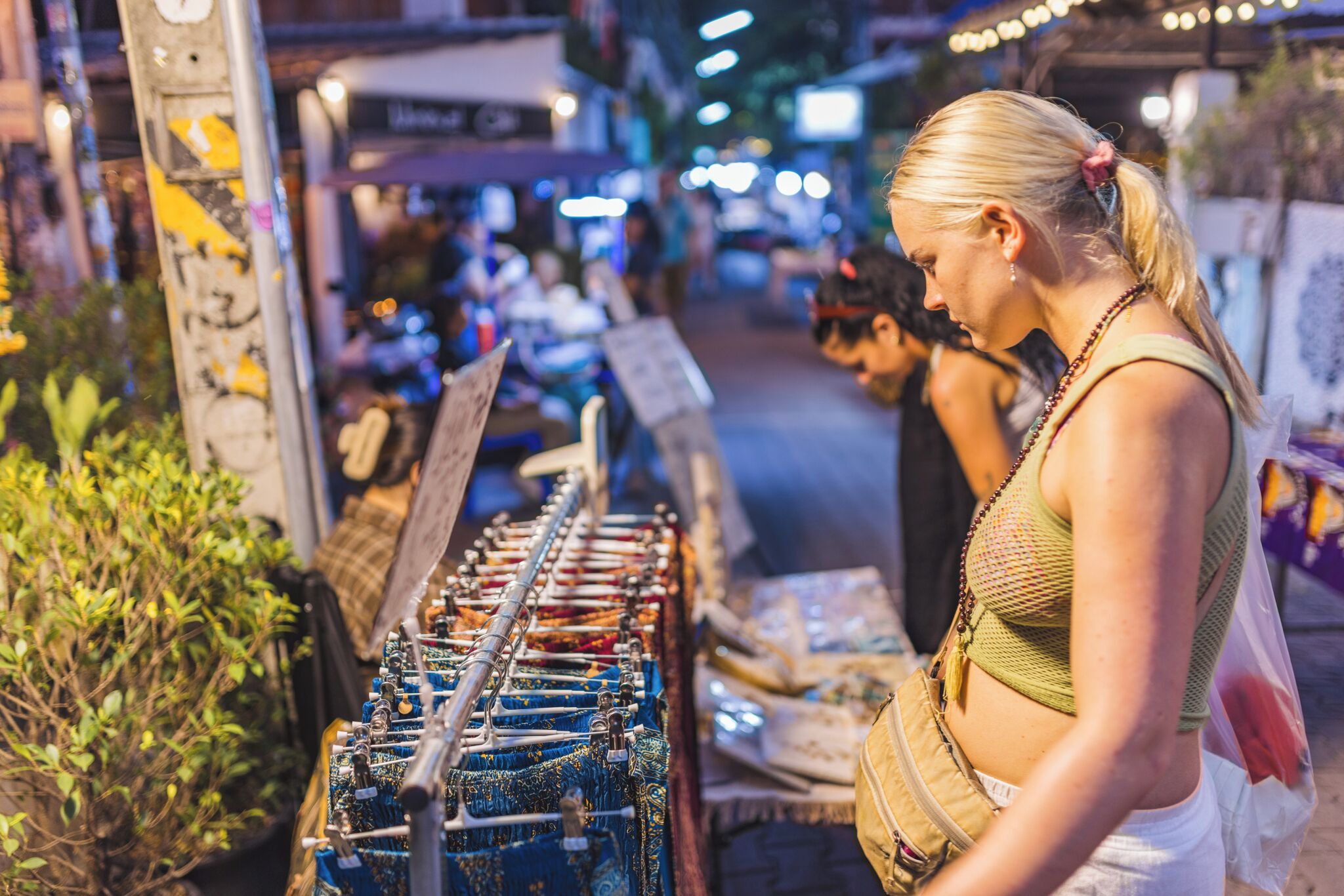 A person examining items at a market stall with various goods on display.