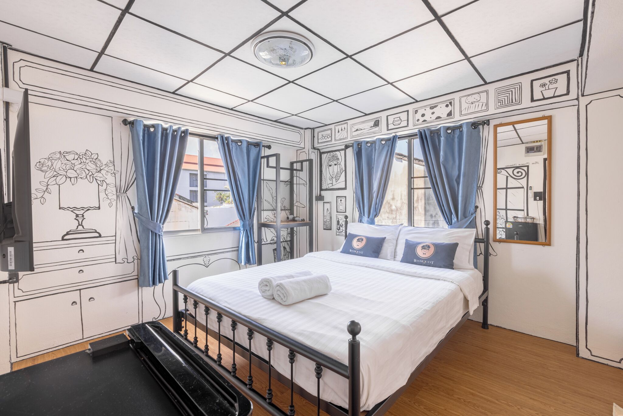 A bedroom with a bed, curtains, a dresser, a mirror, and wall art.