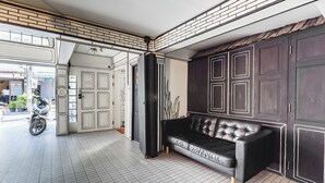 A modern interior with a black leather sofa, a motorcycle, and a brick-patterned ceiling. - RoomQuest Chiang Mai Tha Phae (Chiang Mai)