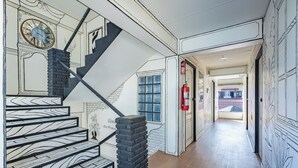 A hallway with a staircase, a fire extinguisher, and a door leading to another room. - RoomQuest Chiang Mai Tha Phae (Chiang Mai)