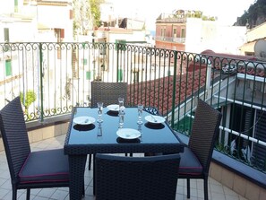 A balcony with a table set for four, surrounded by wicker chairs, overlooking a residential area. - Appartamento a Cetara ID 720 (Cetara)