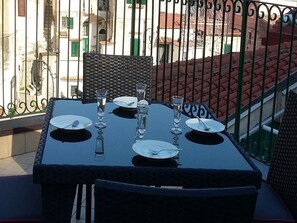 A table set for four with chairs, a balcony railing, and buildings in the background. - Appartamento a Cetara ID 720 (Cetara)