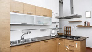 Cuina moderna amb armaris de fusta, una aixeta d'acer inoxidable, una cuina de gas i una campana extractora integrada.