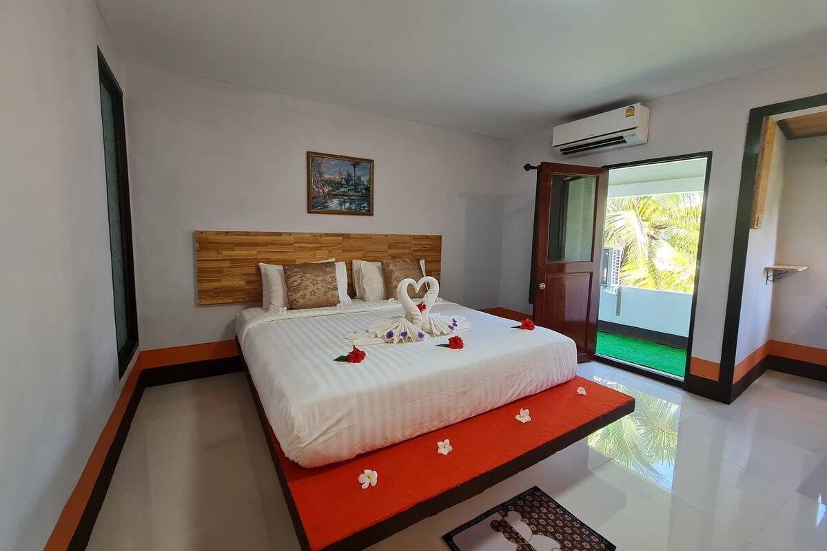 A hotel room with a bed, a painting on the wall, and an air conditioning unit.