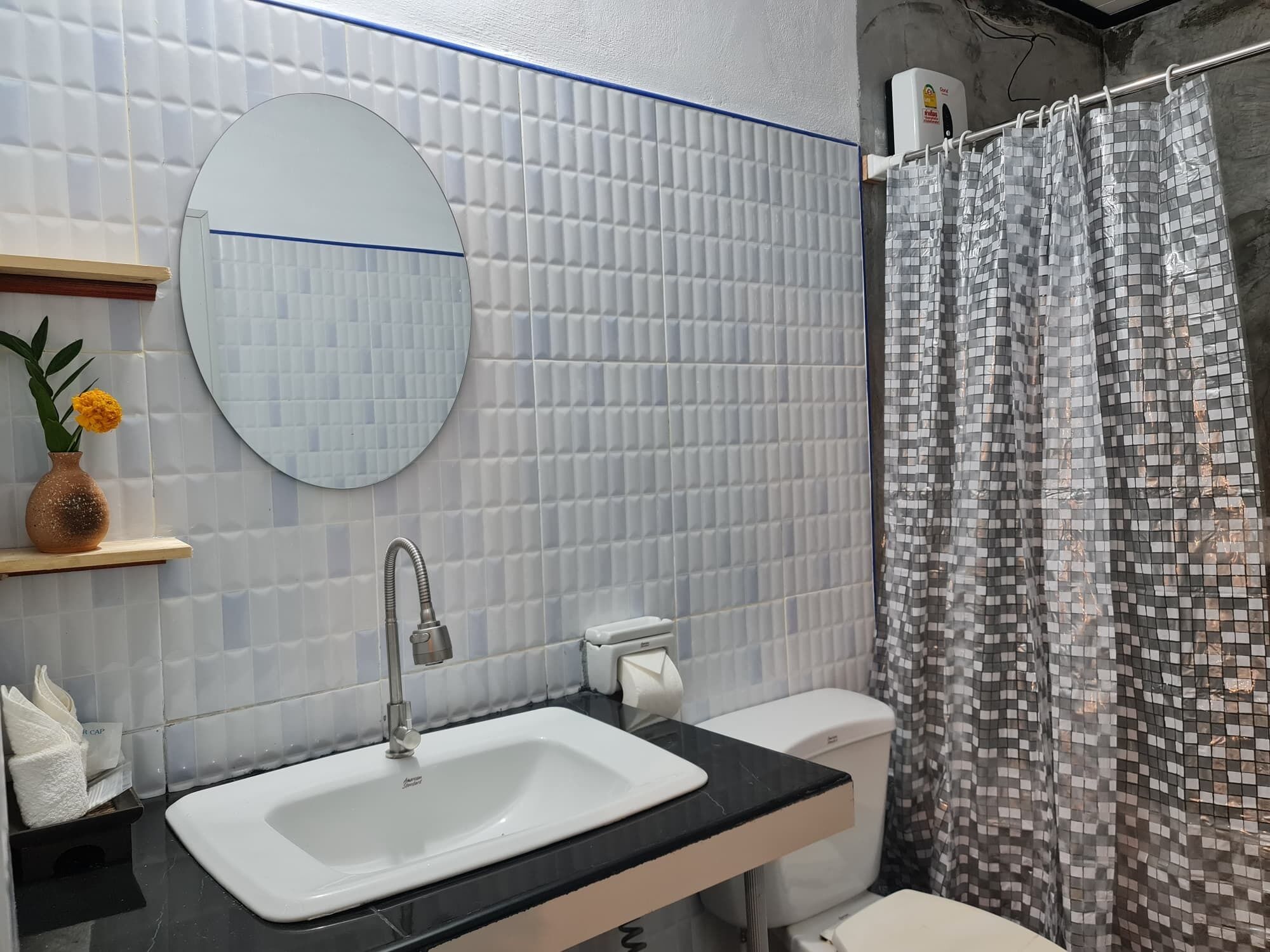 A bathroom with a white sink, a round mirror, a toilet, and a shower curtain.