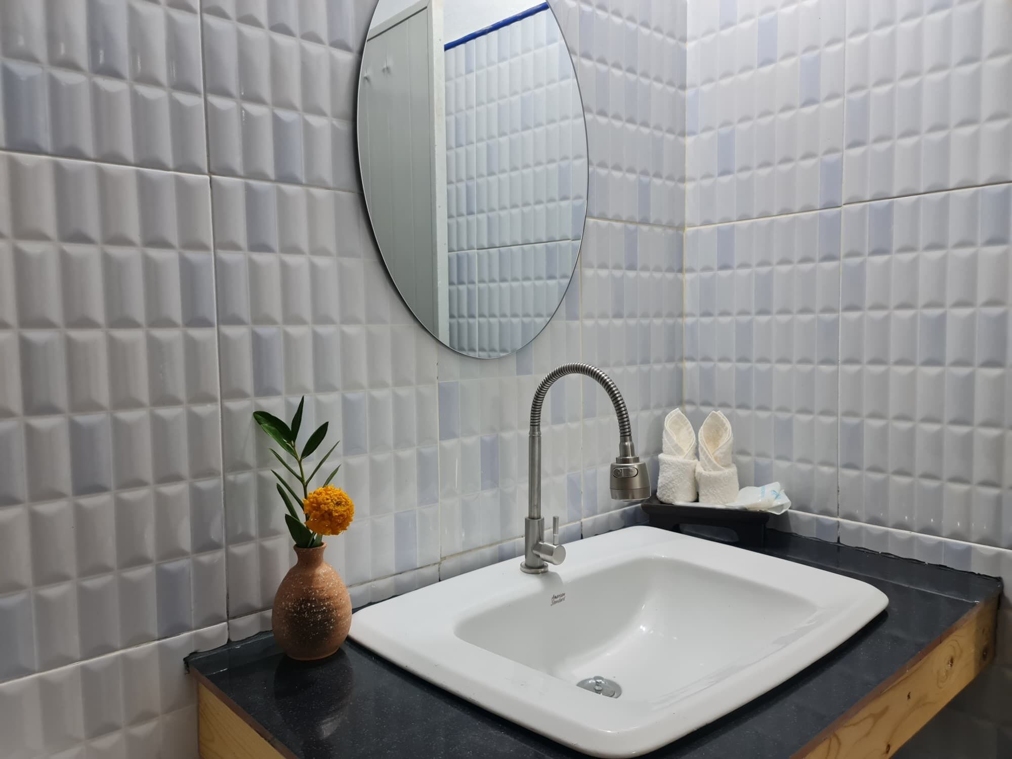 Un baño con lavamanos blanco, un espejo y un perchero para toallas.