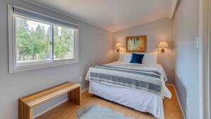 A bedroom with a large window, a bed with a striped blanket, two bedside lamps, and a bench. - Cabin #9 - The Perch at Twin Peaks (Twin Peaks)