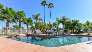 A swimming pool with a tiled edge, surrounded by palm trees and a stone patio. - WALK TO LA-WHITE SOX SP TRAINING 5MN DRIVE 2 STADIUM 1AC YARD +4Ksq ft HOME (Glendale)