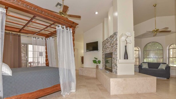 A spacious bedroom with a four-poster bed, a fireplace, a sofa, and a TV. - WALK TO LA-WHITE SOX SP TRAINING 5MN DRIVE 2 STADIUM 1AC YARD +4Ksq ft HOME (Glendale)
