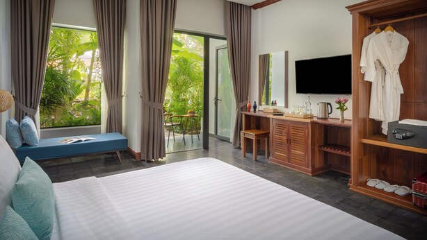 A modern hotel room with a large bed, a desk, a TV, and a wardrobe. - Khmer House Boutique (Siem Reap)