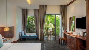 Een hotelkamer met een bed, een bureau, een televisie en uitzicht op de omgeving.