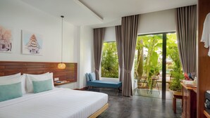 Een hotelkamer met een groot bed, een houten hoofdeinde, een zithoekje en uitzicht op groen.