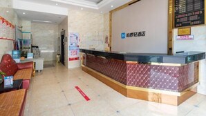 A hotel reception area with a reception desk, seating area, and a bulletin board. - Hongli Business Hotel (Foshan)