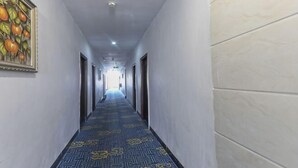 A long hallway with patterned carpet, white walls, and doors on both sides. - Hongli Business Hotel (Foshan)