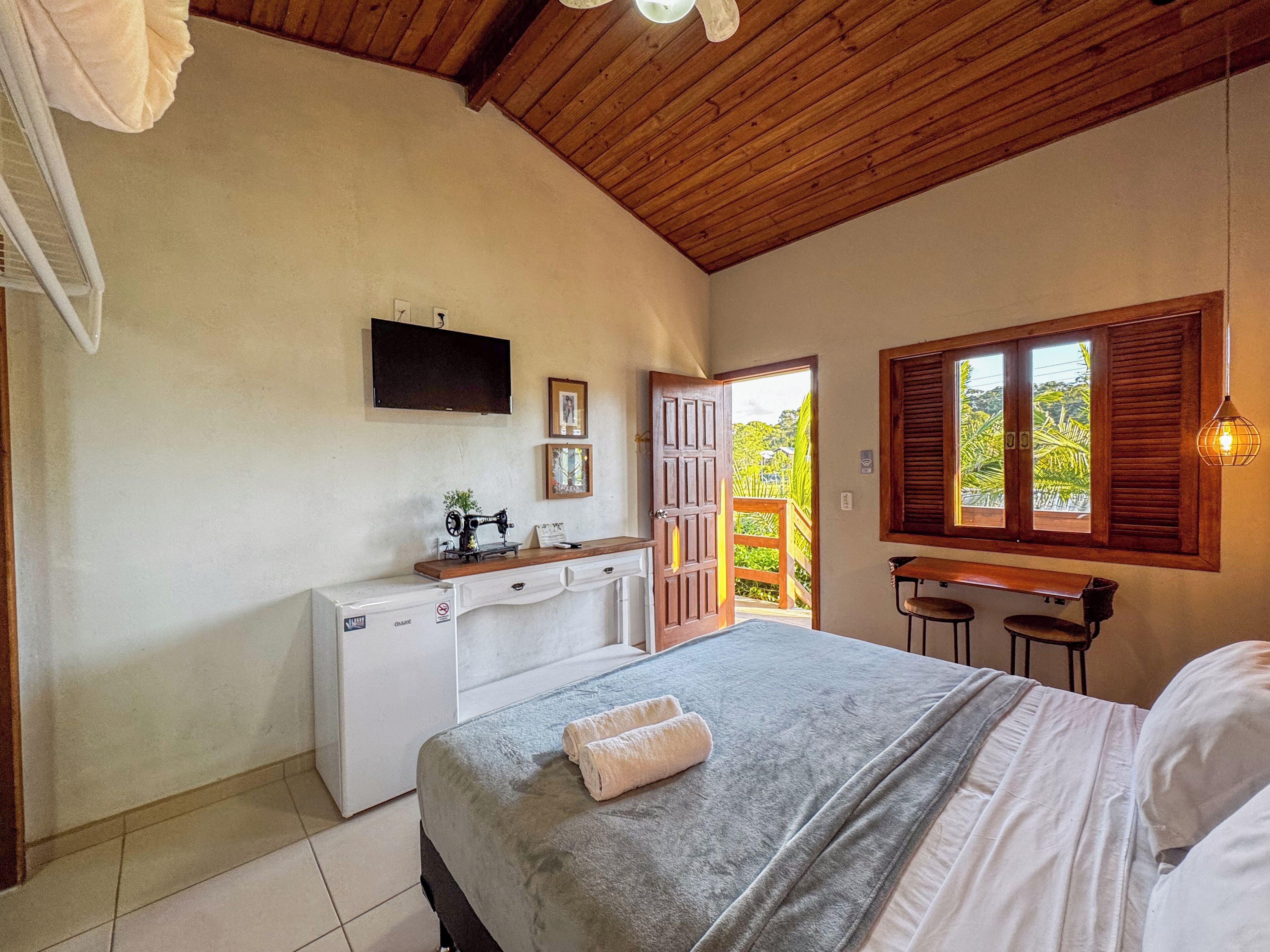 A bedroom with a bed, a desk, a chair, a washing machine, and a television on the wall.