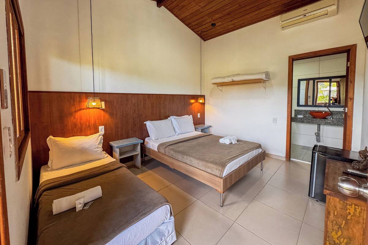A hotel room with two beds, a small kitchenette, and a bathroom.
