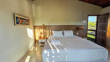 Un dormitorio con una cama grande, una mesita de noche, una lámpara de pared y una puerta que da a un balcón.