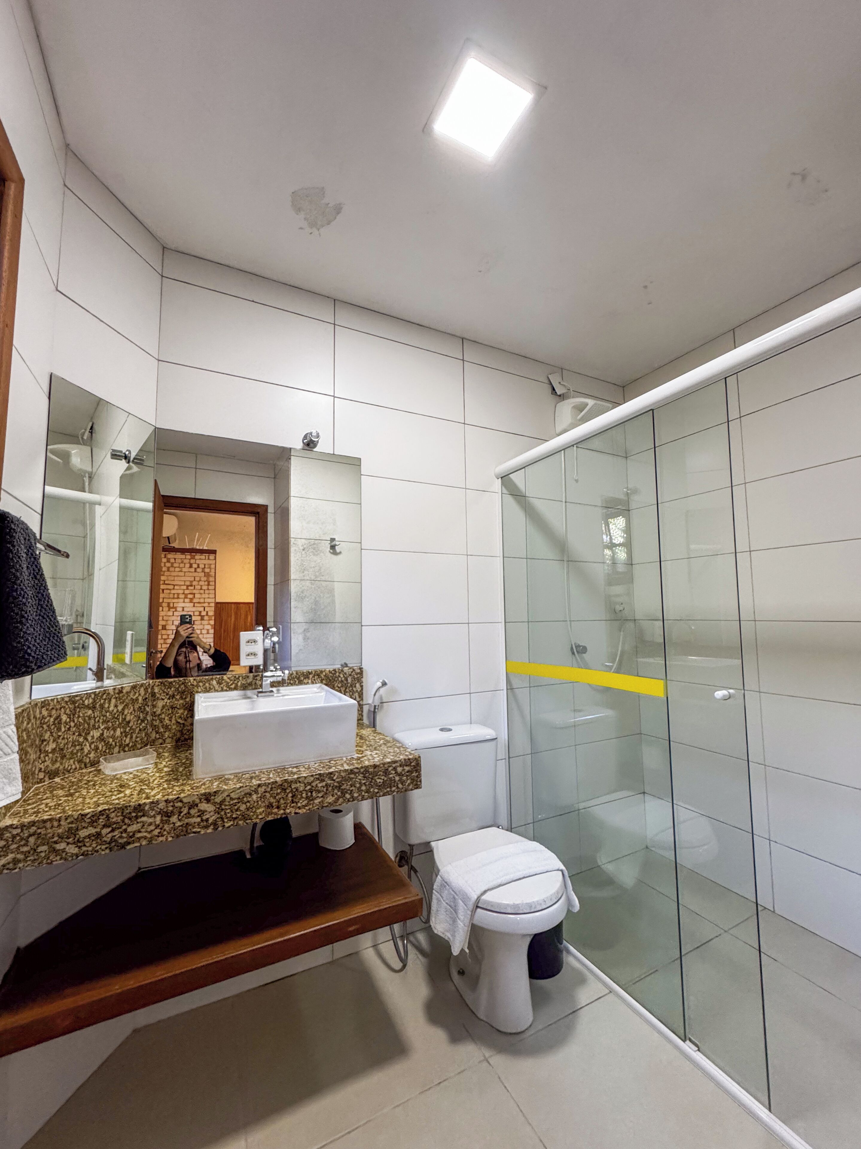 Un baño moderno con lavamanos de granito, espejo, inodoro y cabina de ducha de vidrio.