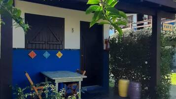 Un edificio con fachada azul y blanca, una puerta de madera, una pequeña mesa y silla afuera, y un letrero que dice "CAFE".