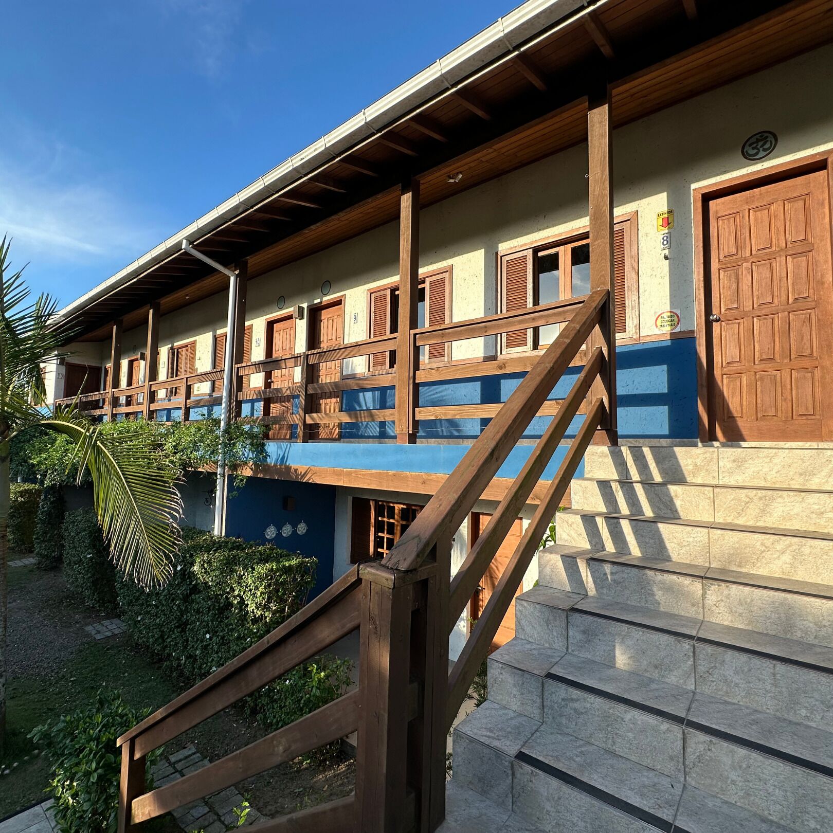A two-story building with wooden balconies, a staircase, and a blue and beige color scheme.