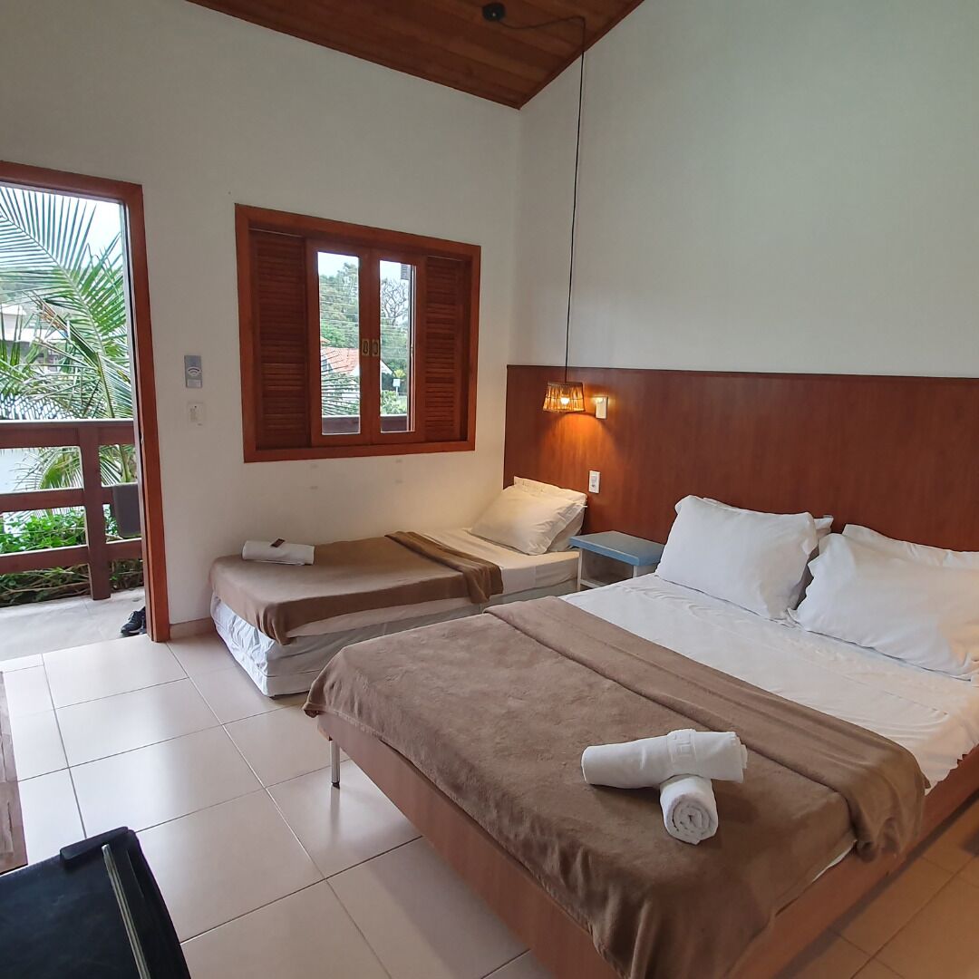 Un dormitorio con dos camas individuales, cabecero de madera, mesita de noche y ventana con contraventanas.