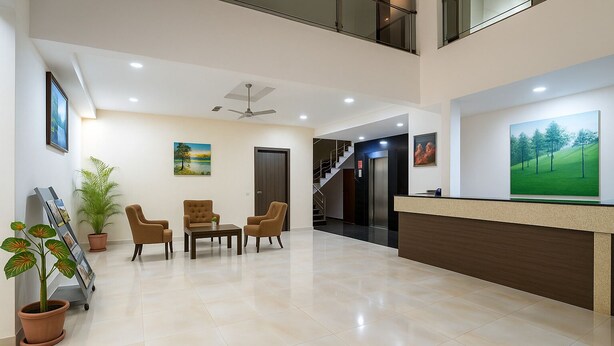Un amplio vestíbulo con mostrador de recepción, zona de estar y escalera que conduce a un nivel superior.