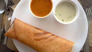 Un plato con un crepé enrollado, un tazón de sopa y una cuchara.