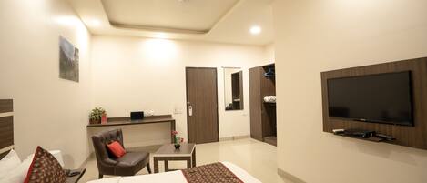 A hotel room with a bed, a desk, a chair, a TV, and a wardrobe.